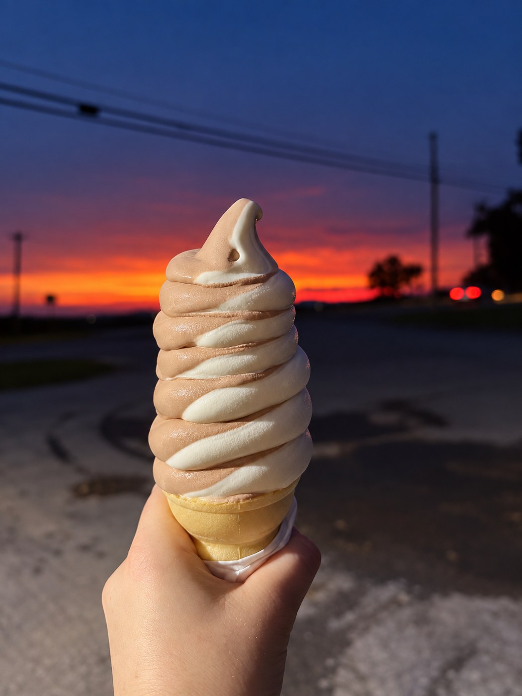 Chocolate and vanilla twist soft serve in a cone at sunset