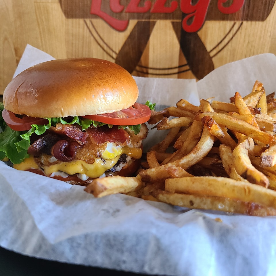Lizzy’s burger with bacon and egg beside fries in a paper-lined basket