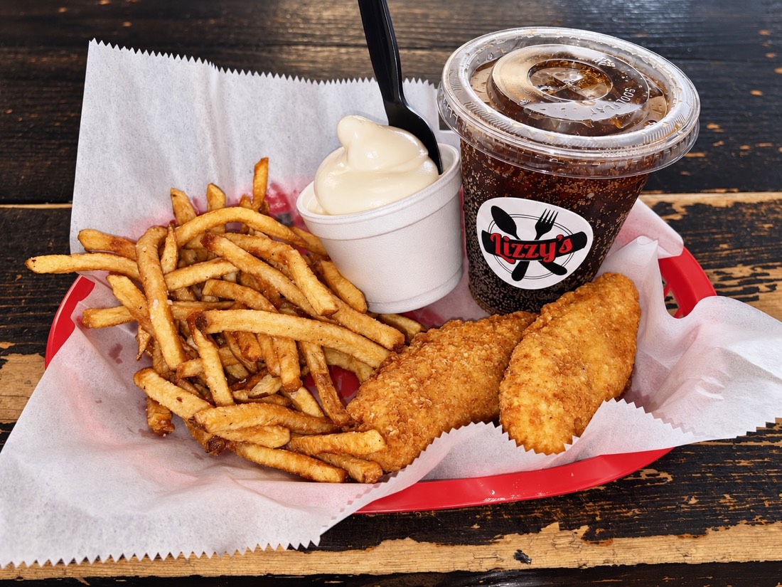 Chicken tenders and fries in a red basket with a small drink and kiddie soft serve