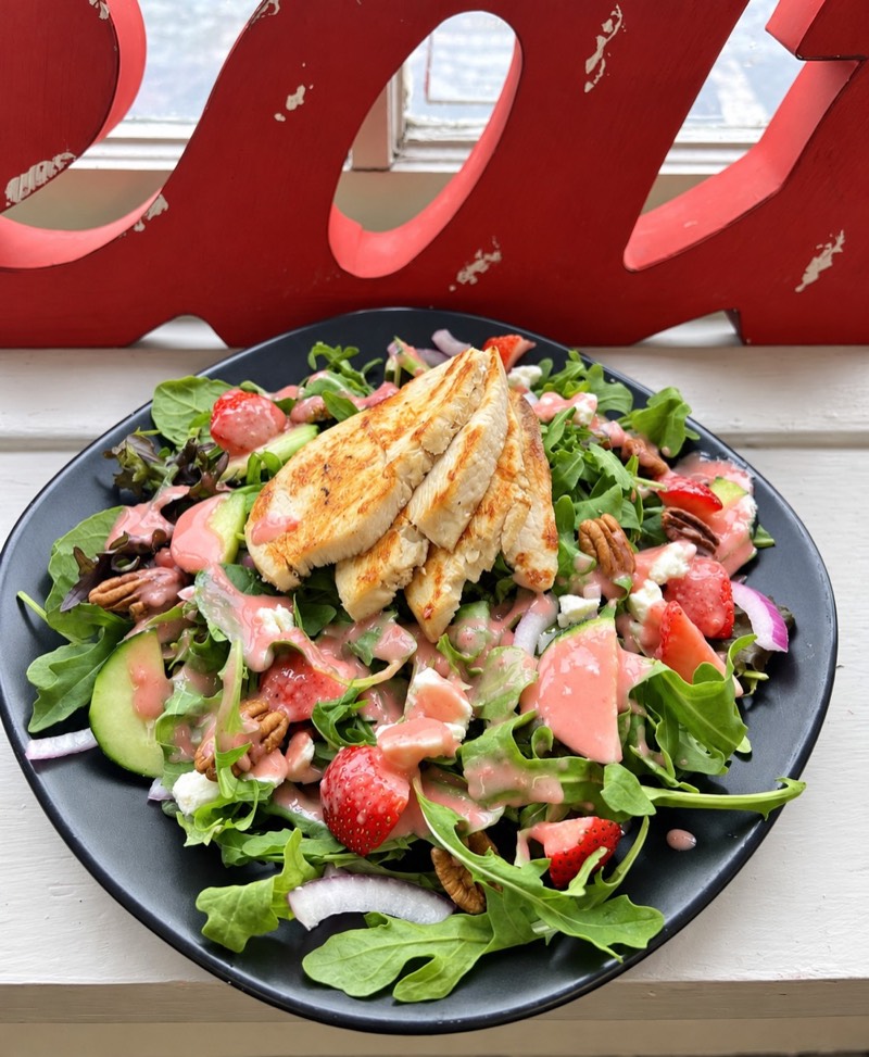 Salad topped with chicken, strawberries and dressing